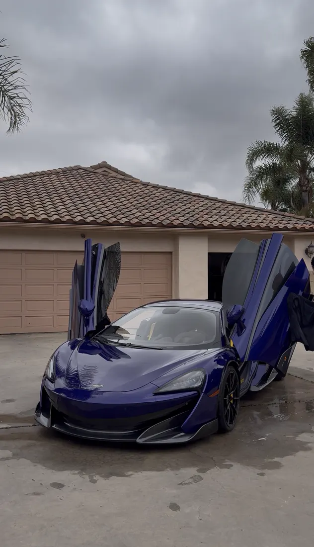 Purple McLaren with doors up after a wash